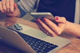 Frau am Handy und Notebook Eine Frau arbeitet am Notebook und hält parallel ihr Smartphone in der Hand.